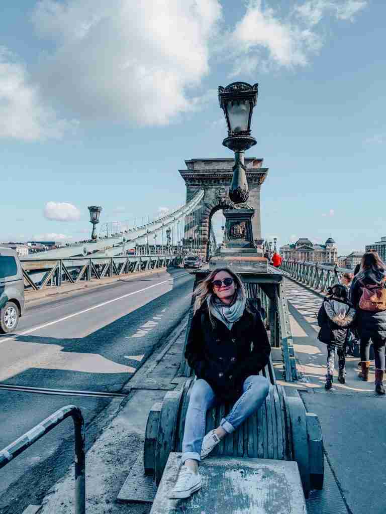 girl sitting on a bridge smiling in Budapest