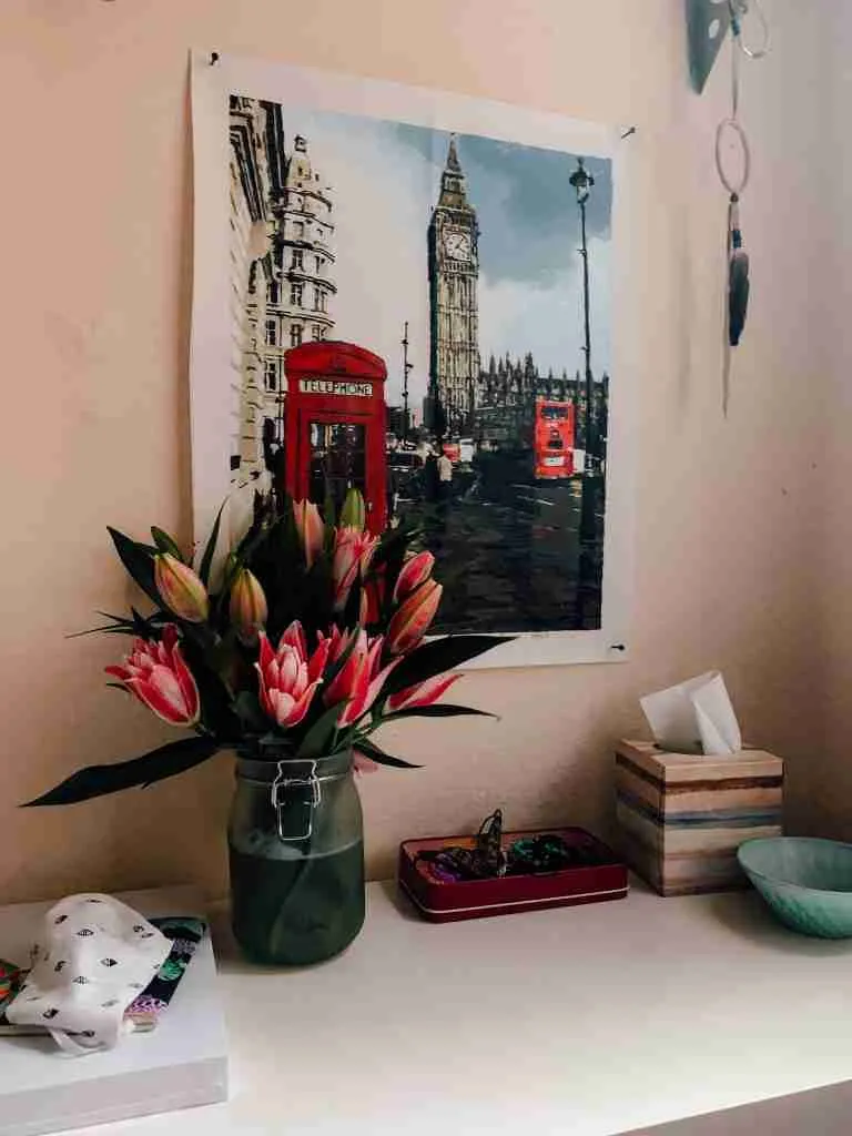 a desk with flowers and a painting of London on the wall