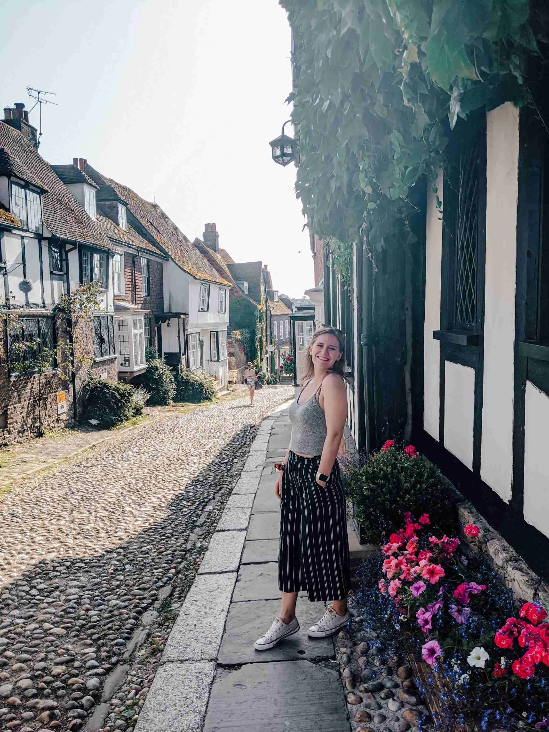 the a girl standing in front of a timber-framed street in Rye - an underrated day trip from London 