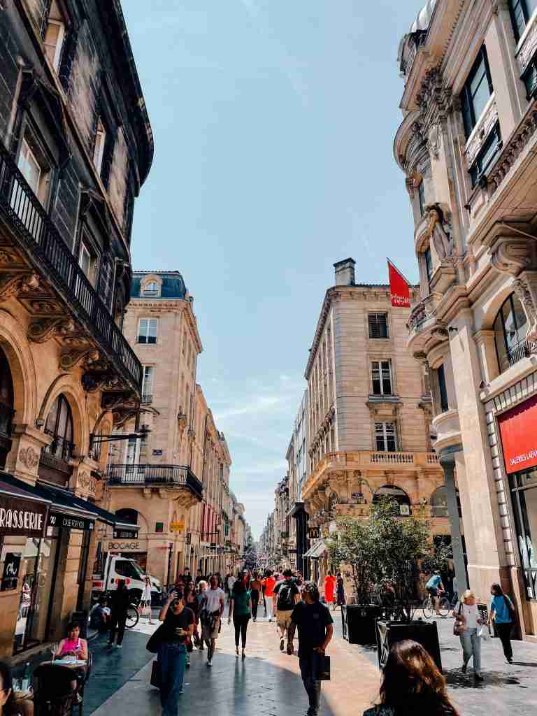 A long street in Bordeaux with pedestrians walking down the middle.