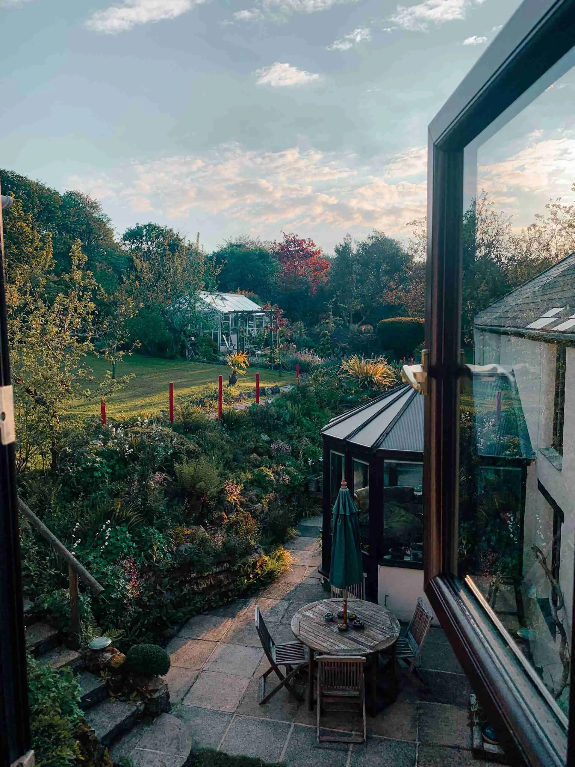 a view out of the window of our Airbnb in Cornwall. The photo is taken from inside looking out their window on their beautiful patio and in the background you can see their spacious gardens!
