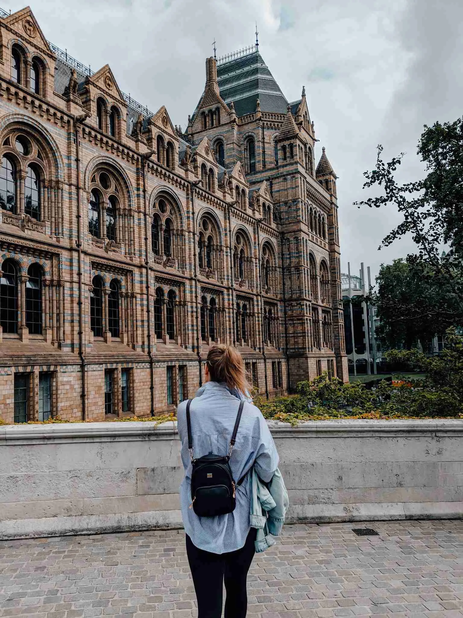A girl walking towards the exterior of the Natural History Museum in London - one of London's museums. 