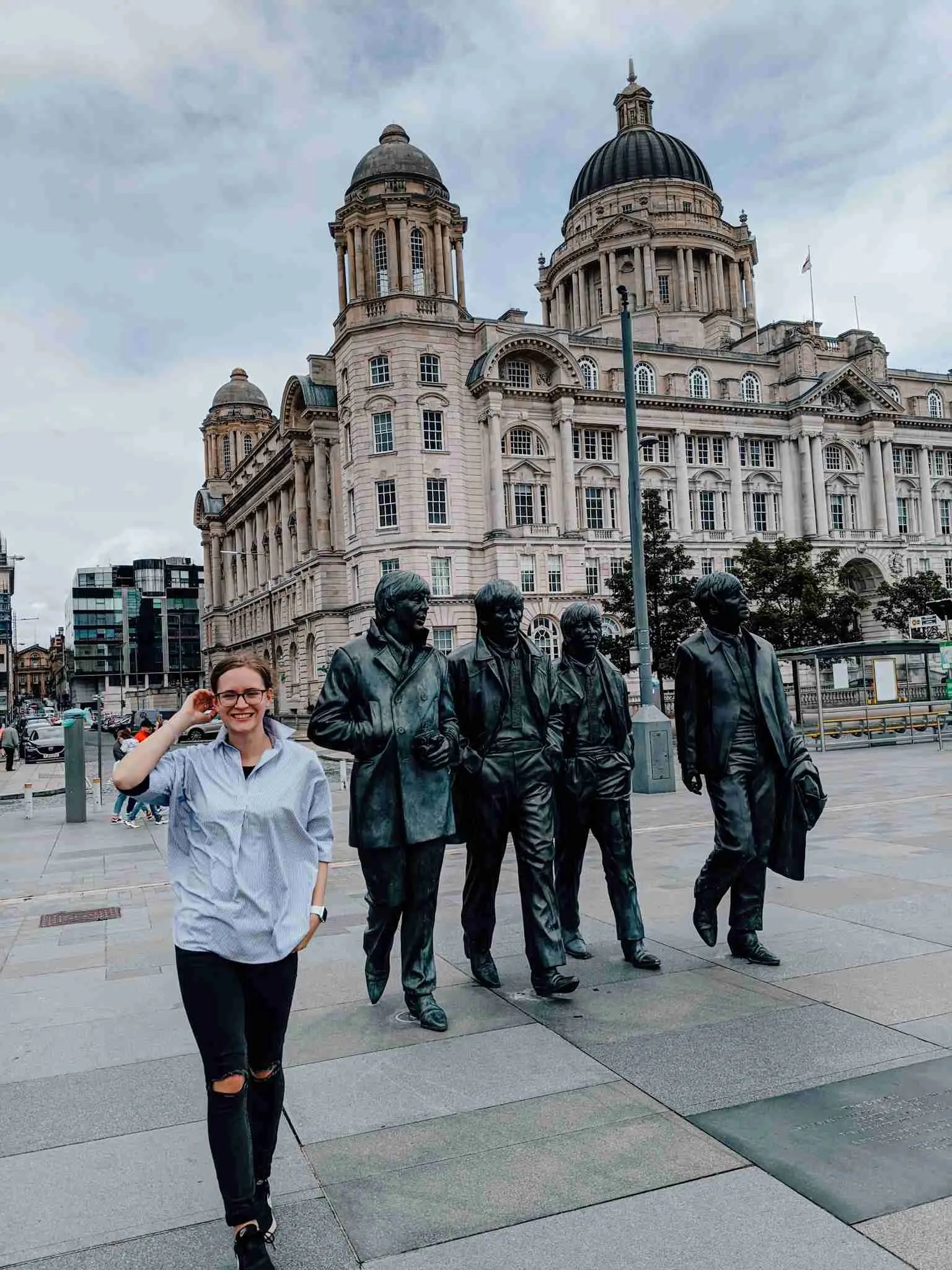 A girl walking away from the Beatles statue in Liverpool, one of the stops on this UK road trip 