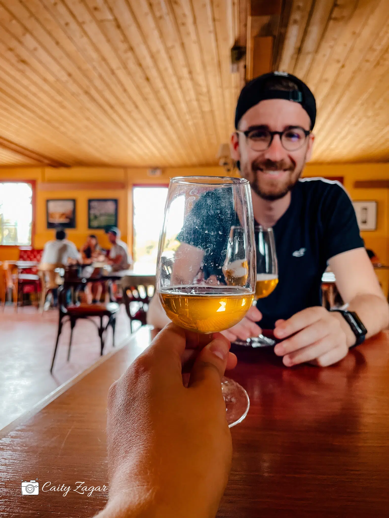 Someone holding up a glass of cider in a dining room during a cider tasting. 