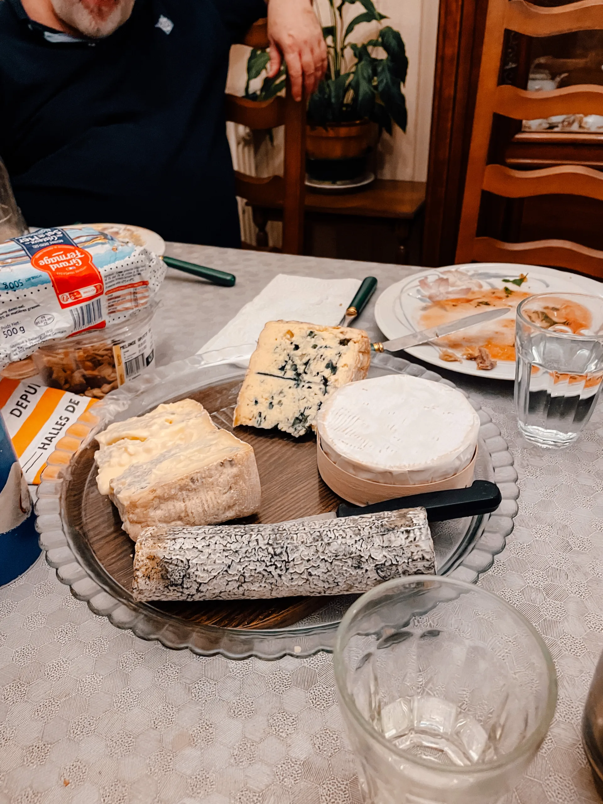 A plate of different french cheeses sit on a dinner table 