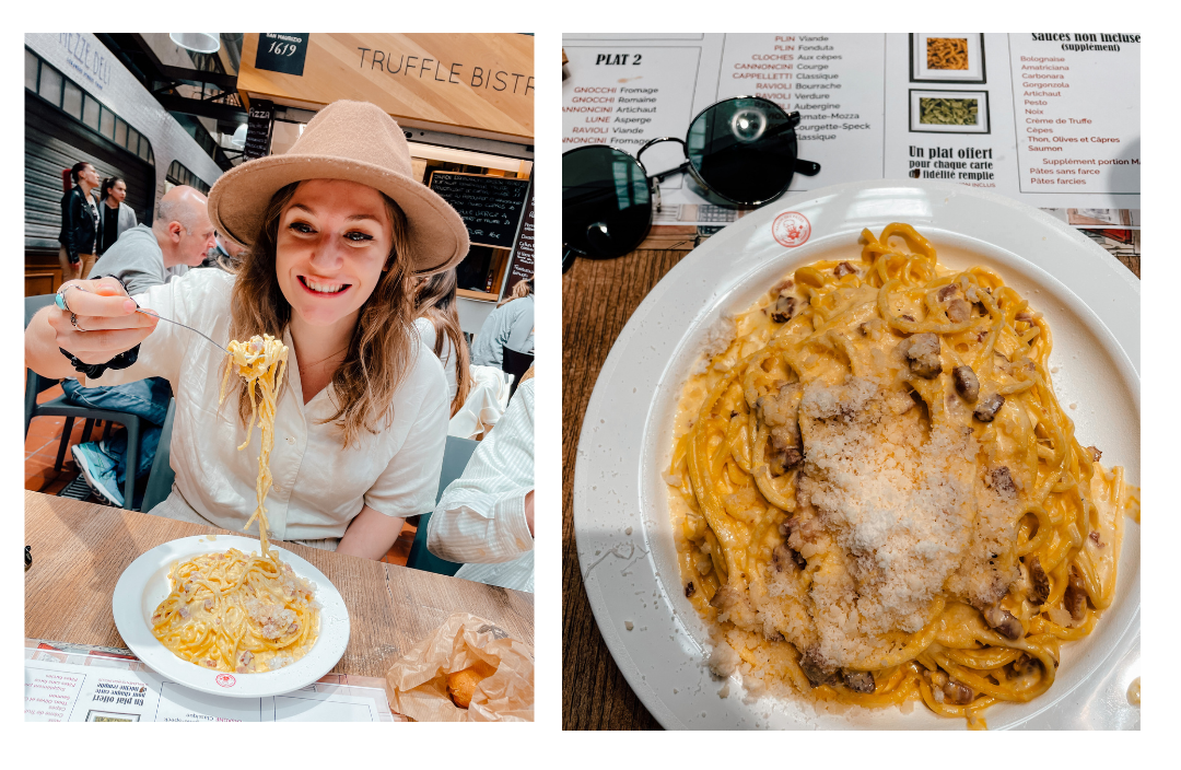 A girl sits pulling long strands of pasta from her plate smiling in delight 