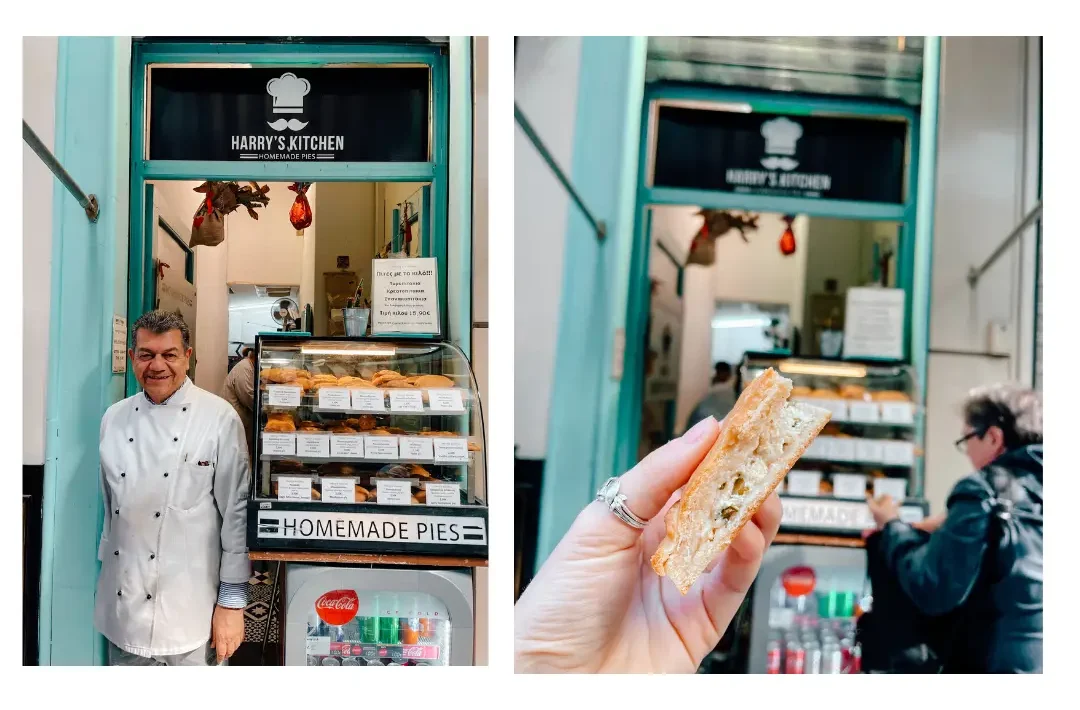 A smiling man stands in front of his greek pie shop with his many flavours of pies on display in the window behind him