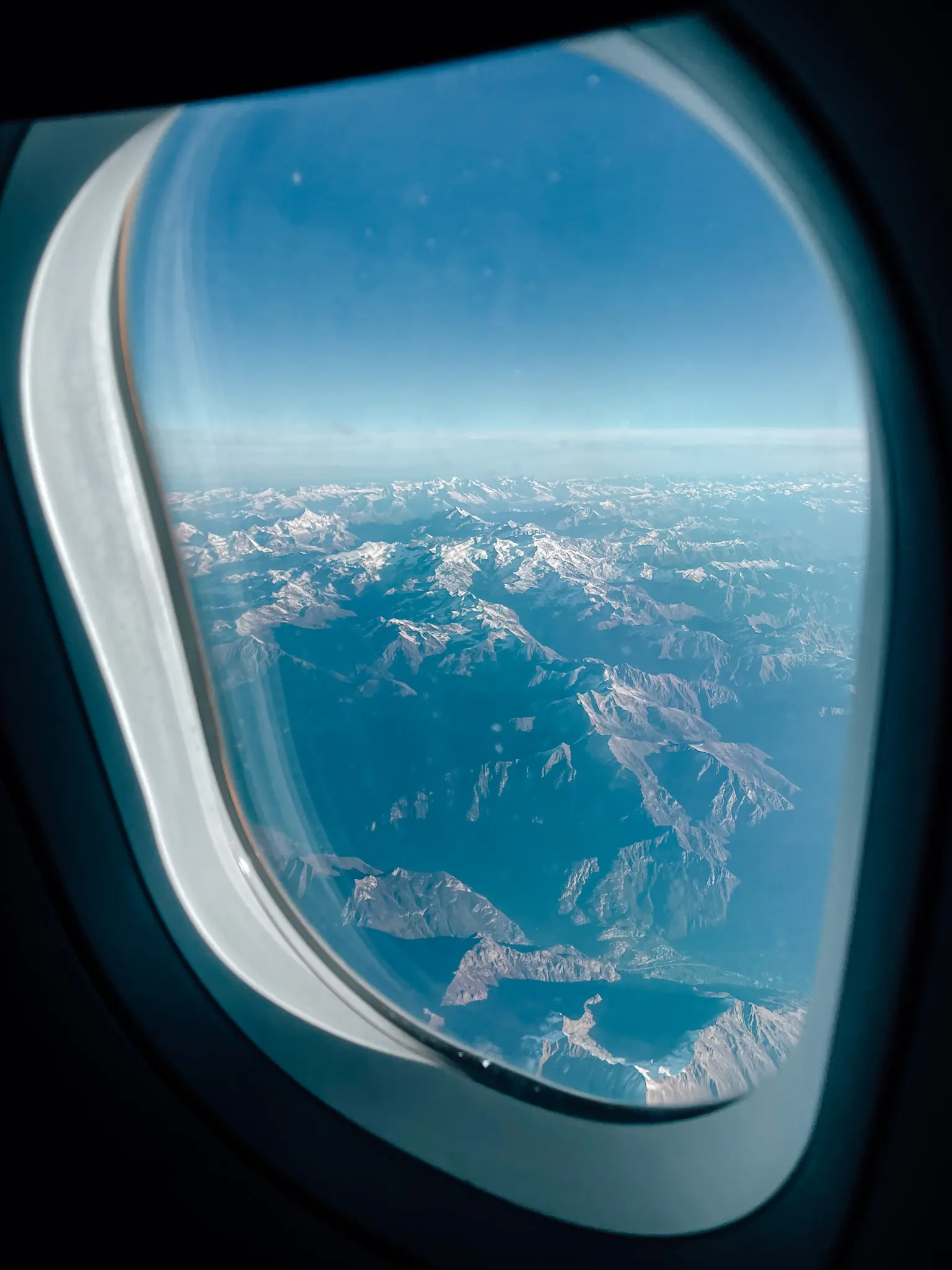 Looking outside a plane window overlooking a snowcapped mountain range using a budget airline to Malta