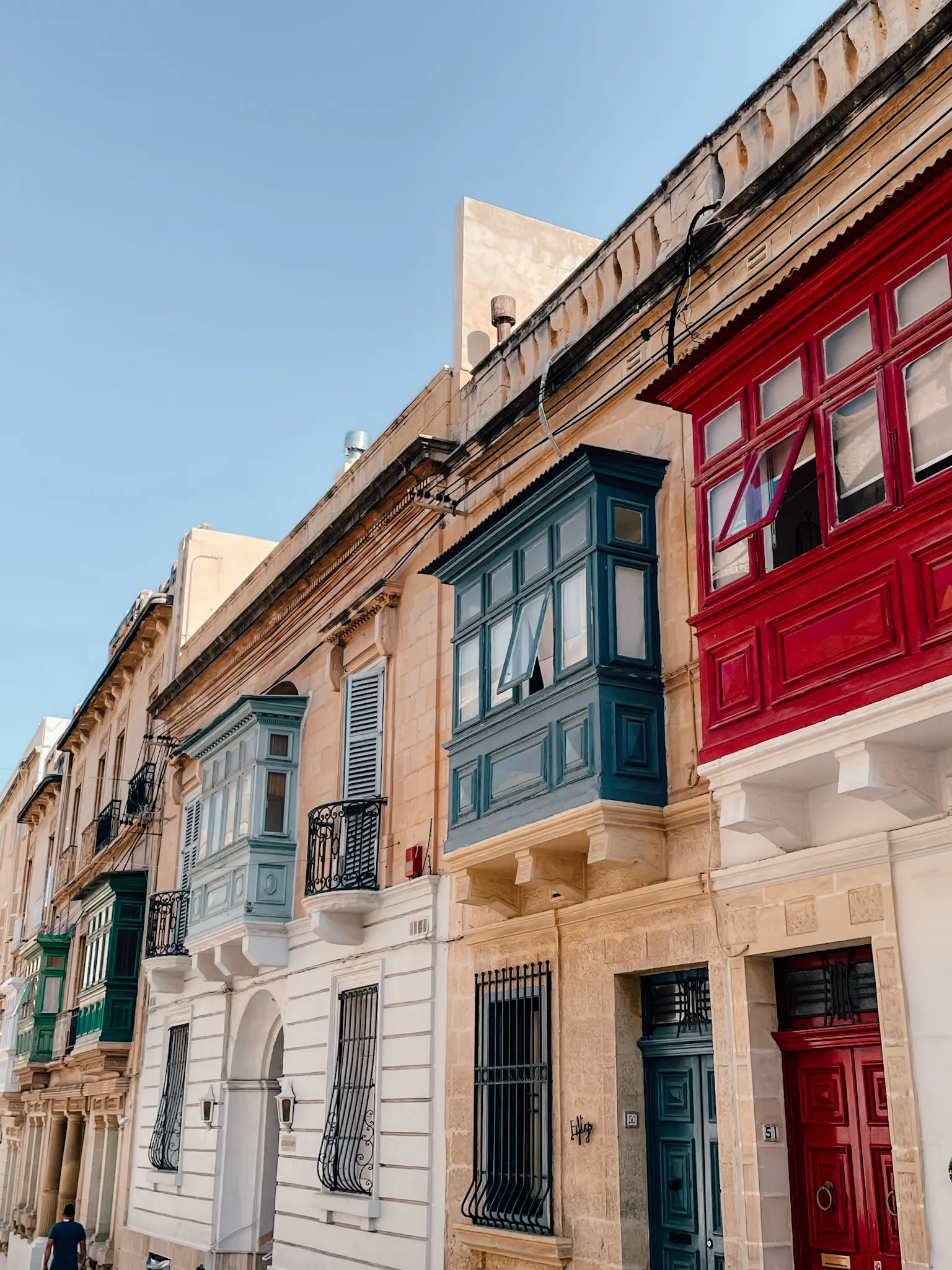 A street in Malta with colorful blue and red balconies.