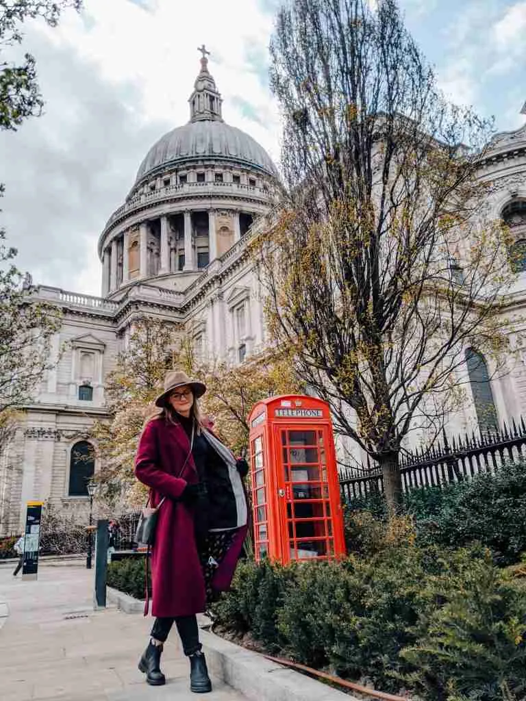 girl walking in front of st Pauls Cathedral with a London Phone Booth in the background